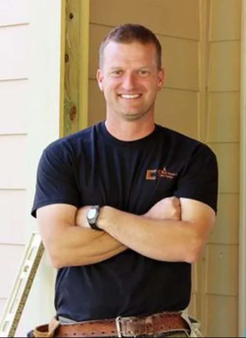 JD Crill standing outside a home with tool belt and level